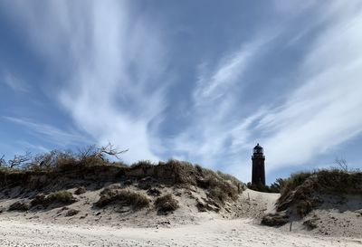 Lighthouse on beach against sky