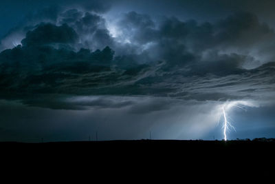 Scenic view of lightning over landscape against storm clouds