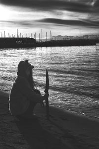 Woman holding stick crouching on sea shore at beach