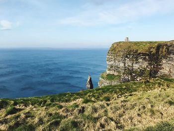 Scenic view of cliff by sea against sky