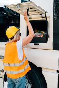 Rear view of woman standing by truck