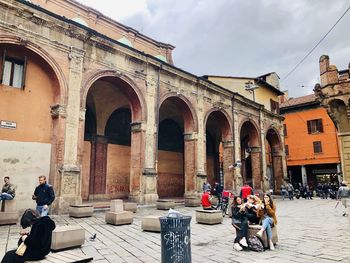 People at historic building in city against sky