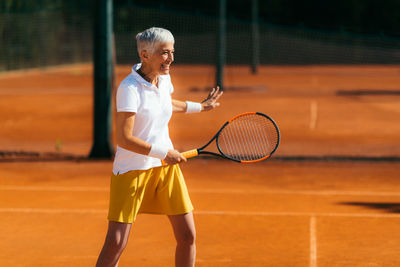 Active senior lady in her 60s playing recreational tennis