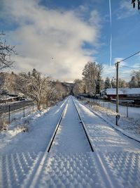 Scenic view of snow covered railway tracks against sky