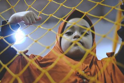 Portrait of girl wearing hijab seen through metal fence