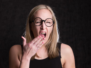 Portrait of young woman wearing mask against black background