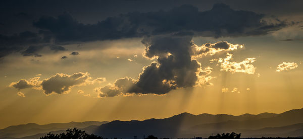 Sun shining through clouds over mountains