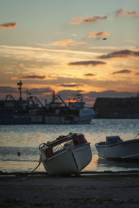 Boat moored on beach against sky during sunset