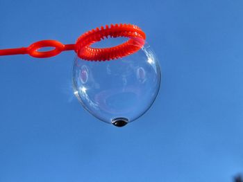 Low angle view of bubble from wand against clear blue sky