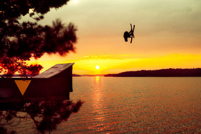 Silhouette of skier above lake at sunset