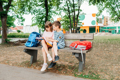 Back to school. schoolchildren with backpacks sit on a bench in the school yard at recess 