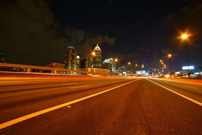 Light trails on road against sky at night