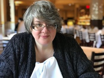 Overweight mature woman wearing eyeglasses sitting in restaurant