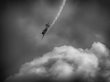 Low angle view of military airplane flying against cloudy sky