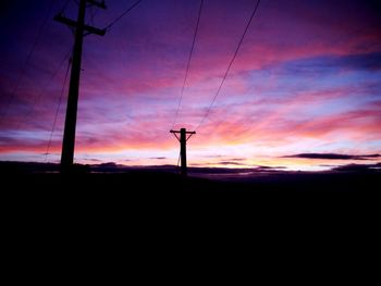 Low angle view of silhouette electricity pylon against sky