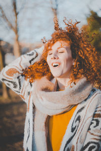 Portrait of smiling young woman standing against tree