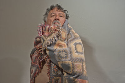 Portrait of young man holding umbrella against wall