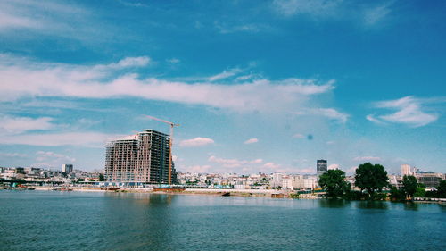 Buildings by river against sky in city