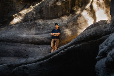 Tens boy leaning up against rock