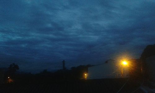 Low angle view of illuminated trees against dramatic sky