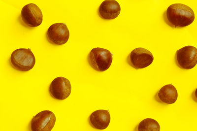 High angle view of chestnuts arranged against yellow background