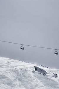 Low angle view of overhead cable car against sky during winter