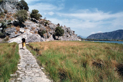 Rear view of man walking on footpath against sky