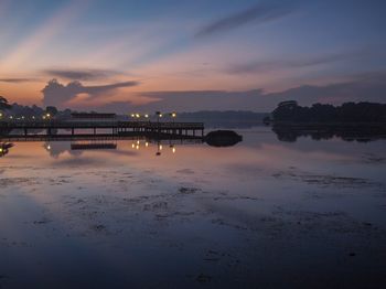 Reflection of pier on sea against sky during sunset