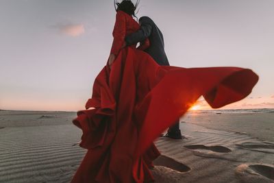 Low angle view of couple walking at beach against sky