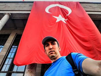 Low angle view of man standing against turkish flag at building