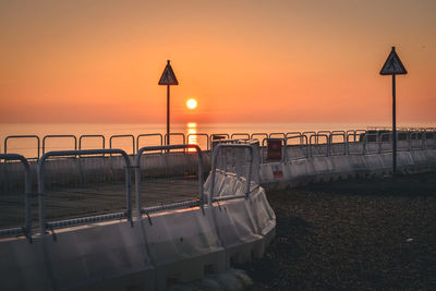 Lifeguard hut on beach against orange sky