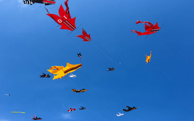 Low angle view of flags against clear blue sky