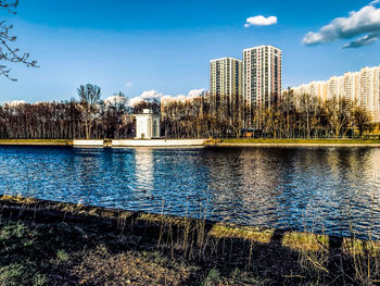 Buildings by lake against sky in city