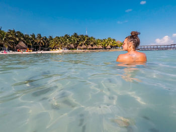 Rear view of woman swimming in sea against sky