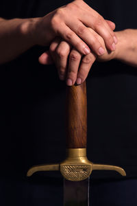 Close-up of man holding hands over black background