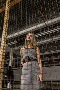 Young woman standing against metal grate