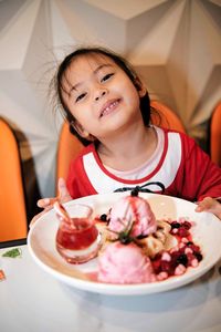 Little child eating strawberry ice cream in red christmas costume happy and smiling