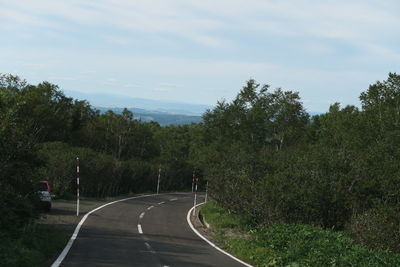 Road by trees against sky