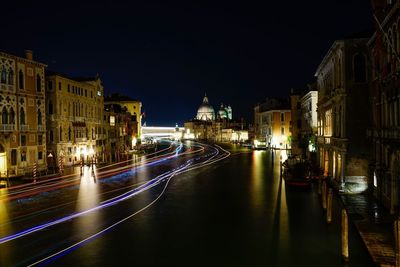 Illuminated street amidst buildings in city at night