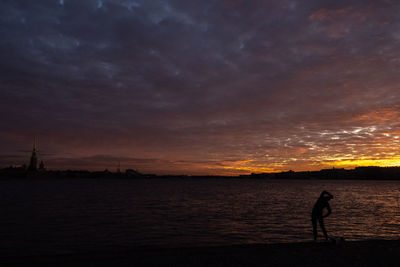 Silhouette man standing on beach against sky during sunset