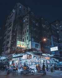 People on illuminated street amidst buildings in city at night