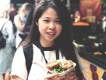 Close-up portrait of young woman having street food