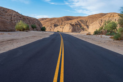 Empty road by mountain against sky