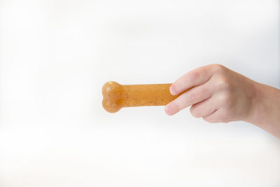 Close-up of hand holding ice cream over white background