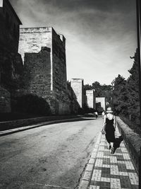 Rear view of woman walking on footpath in city