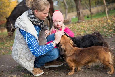 Happy family-mother with  children hugging and feeds pets dogs, cats and goats in countryside farm