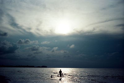 Silhouette people on beach against sky