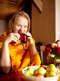 Portrait of smiling beautiful woman having tea by table at home