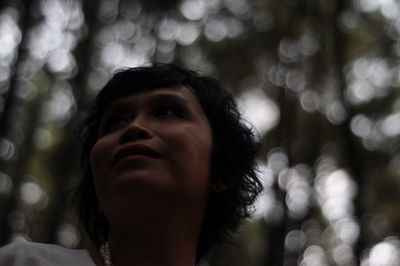 Close-up low angle view of mature woman looking away in forest