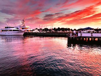 Boats moored at harbor against sky during sunset